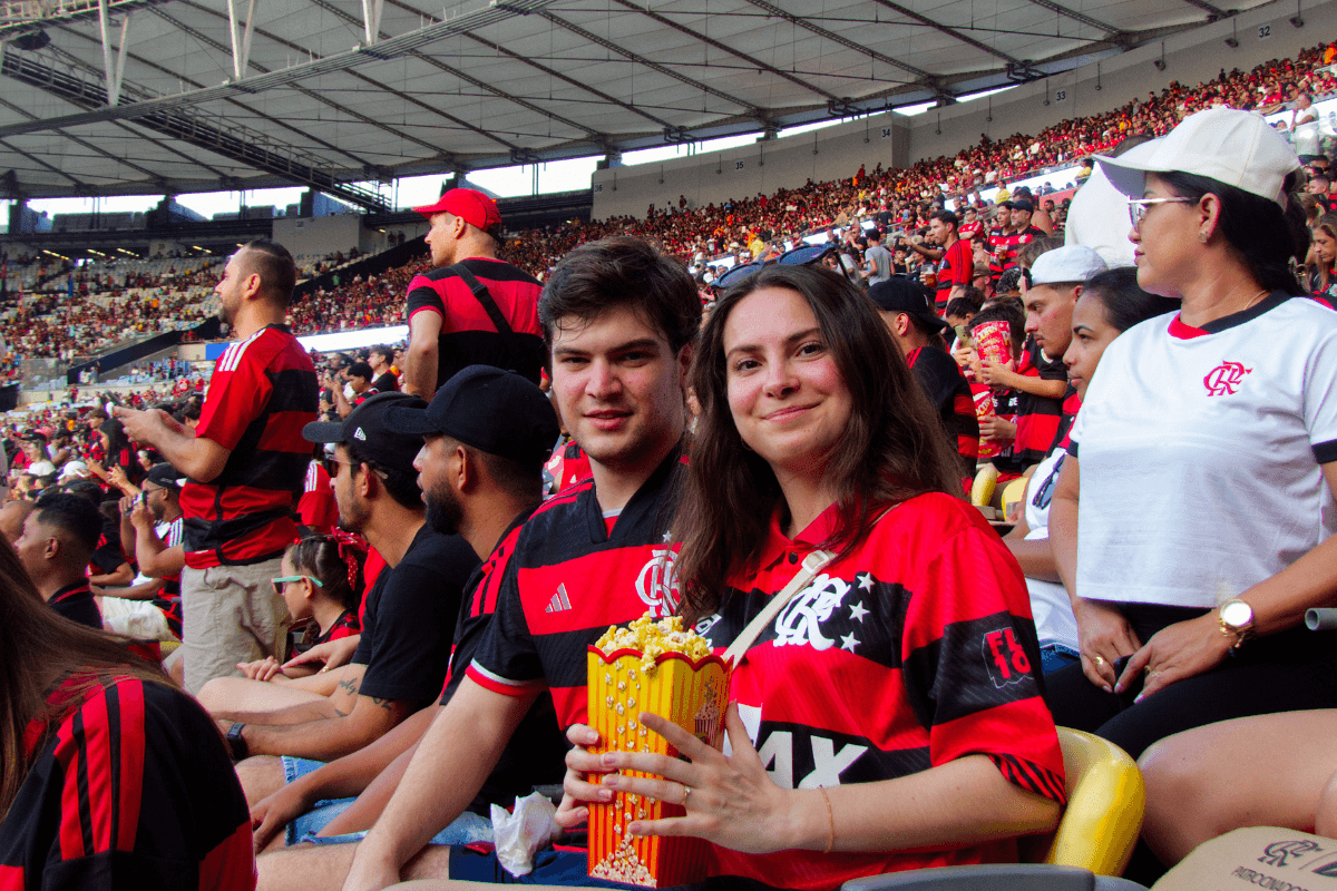 Casal de torcedores com camisas do Flamengo sorrindo na arquibancada do Maracanã